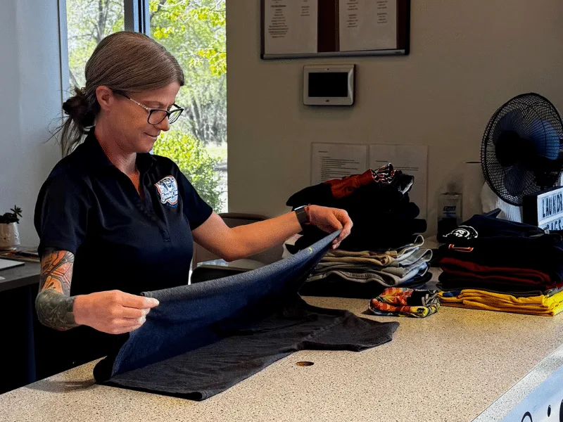 Sandy Creek Laundromat employee professionally folding laundry